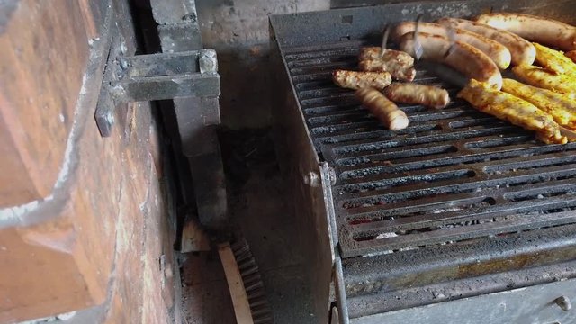 Male hand taking off grill finished minced meat rolls cevapcici in glass bowl. Filmed while grilling mixed meat with vegetables on charcoal grill.
