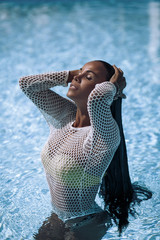 fashion sexy tan young brunette girl in erotic white mesh transparent shirt standing in the pool...