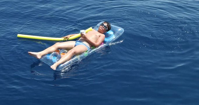 Teenager boy on the inflatable mattress playing on the sea 6