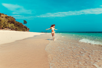 Fototapeta na wymiar Beautiful emotional Model Girl walking alonh the beach and laughing. Beautiful Woman Hot Girl enjoying the Ocean. Tropical vacation.