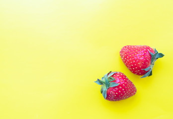 two strawberries on a bright yellow background