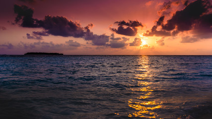 Fototapeta na wymiar A sunrise facing the sea in Raa Atol, in the Maldives, with clouds and an intense red