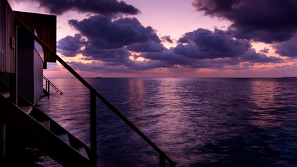 Contemplating a bluish and magenta sunset covered with clouds in the Maldivian island