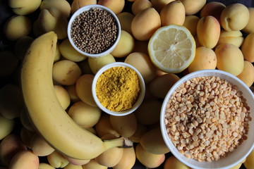 Yellow food background of apricots, banana, lemon, lentil, coriander seeds, turmeric
