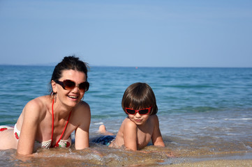 Mother and son enjoying on beach. Happy family relax on sea on summer vacation