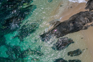 Fototapeta premium Portret moda styl życia na zewnątrz ładna dziewczyna leżącego na dużych kamieniach w morzu. Ubrana w stylową krótką różową sukienkę. Samotny. Sztuka fotograficzna. Twórczy. Widok z góry