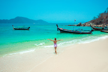 Happy traveler woman arms open in dress relaxing and looking to the beautiful nature landscape with traditional long tail boats. Tourist sea beach Thailand, Asia, Summer holiday vacation travel trip -
