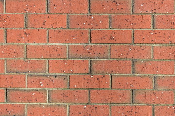 Red brick wall pattern with unevenly distributed small rock chips in brick material.