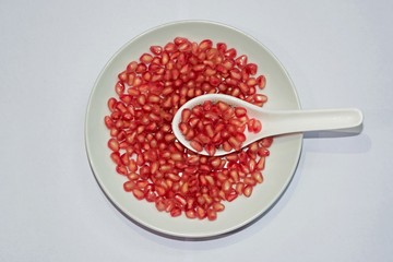 Red Pomegranate seeds on white plate