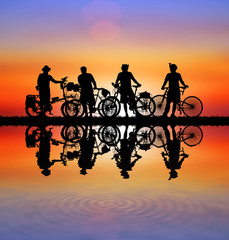 Silhouette group friend  and bike relaxing on blurry sunset background.