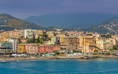 Fototapeta premium View of Genoa (Genova) from the port when arriving by ship, at sunrise with its yachts and vessels along the water.