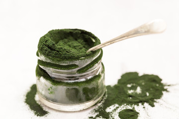 Spirulina green powder, close up with spoon and isolated spirulina powder. Mineral and vitamin intake to improve diet and healthy lifestyle.