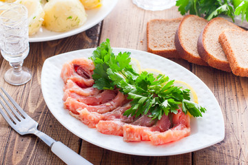 Homemade red salted fish on a white bowl on a background of boiled potatoes, horizontal