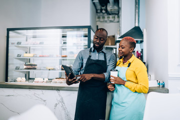 Black cafe workers browsing tablet during break