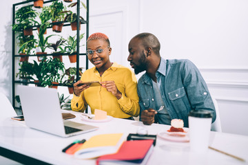 Black man looking at colleague taking photo of cake