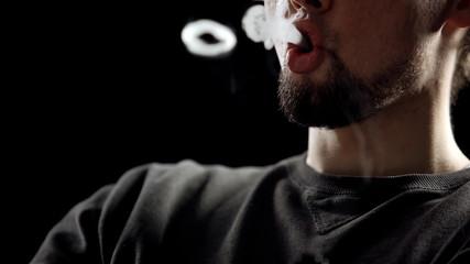 Young man blowing smoke rings, hipster generation, nicotine addiction closeup