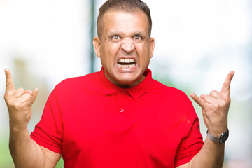 Middle age arab man over isolated background shouting with crazy expression doing rock symbol with hands up. Music star. Heavy concept.