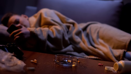 Nicotine addicted teenager covered with blanket scrolling phone, feeling cold