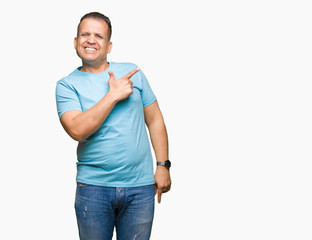 Middle age arab man wearing blue t-shirt over isolated background cheerful with a smile of face pointing with hand and finger up to the side with happy and natural expression on face