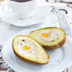 Baked avocado with egg for breakfast on white plate, square