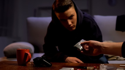 Drug dealer offering addicted teenager weed dose, criminal activity, abuse - obrazy, fototapety, plakaty