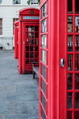Fototapeta na wymiar Red phone booth detail - a row of British phone boxes, bright red in color, located on a London street