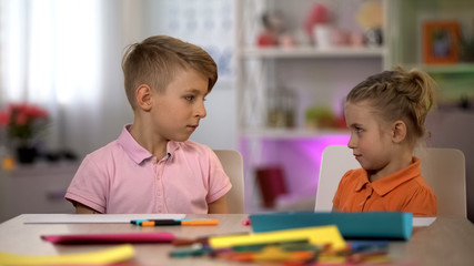 Offended siblings looking at each other, children quarreling, misunderstanding