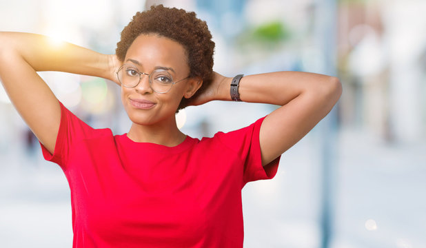 Beautiful young african american woman wearing glasses over isolated background Relaxing and stretching with arms and hands behind head and neck, smiling happy