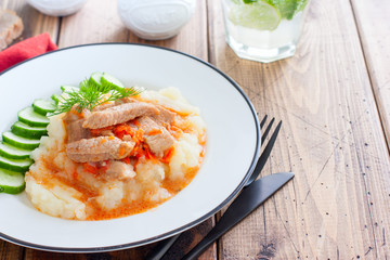 Pork slices with tomato sauce and mashed potatoes on a wooden table, horizontal, copy space