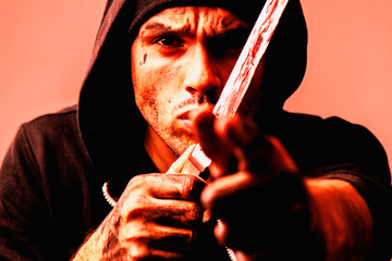 Portrait of aggressive robber with knife stylized in red light.