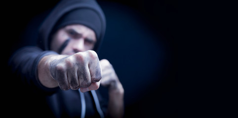 Portrait of aggressive man giving a punch. Robbery and konflict concept. Selective focus on fist.