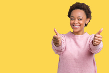 Beautiful young african american woman over isolated background approving doing positive gesture with hand, thumbs up smiling and happy for success. Looking at the camera, winner gesture.