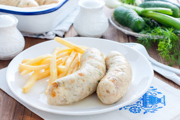 Homemade sausages with chicken and french fries on a white plate, horizontal