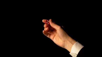 Fototapeta premium Hand showing dice against black background, risk and success in gambling, casino