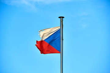 Tattered Czech Republic flag against blue sky blowing in the wind with copy space