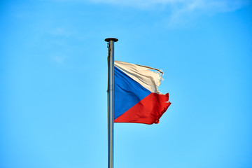 Tattered Czech Republic flag against blue sky blowing in the wind with copy space