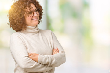 Beautiful middle ager senior woman wearing turtleneck sweater and glasses over isolated background smiling looking to the side with arms crossed convinced and confident