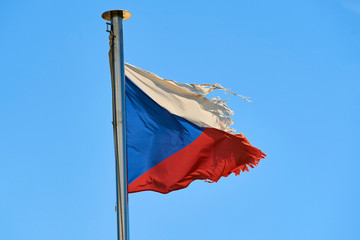 Tattered Czech Republic flag against blue sky blowing in the wind with copy space