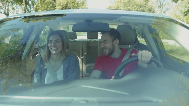 Handsome young Caucasian man giving smartphone to girlfriend. Smiling couple looking out window. Guy pointing finger at fav place. Dating. Daytime. Sunny day. Summertime. Forest.