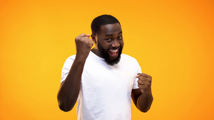 Young black guy showing success gesture with hands, isolated yellow background