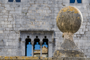 A baluster in front of wall with  medieval windows