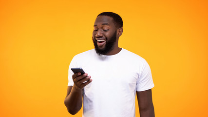 Amazed african man browsing smartphone internet, online application, cash back