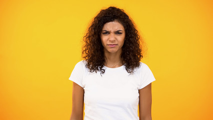 Upset female millennial looking camera on orange background, depression, worries
