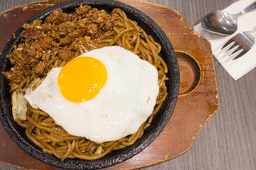 fried egg, spaghetti and chicken on hot black pan and wood tray background