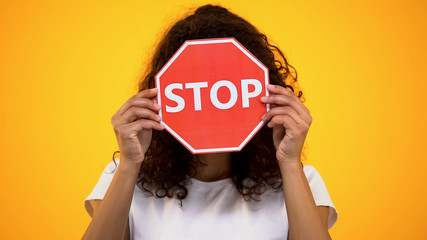 Young woman showing stop sign, protesting against racism and violence, awareness