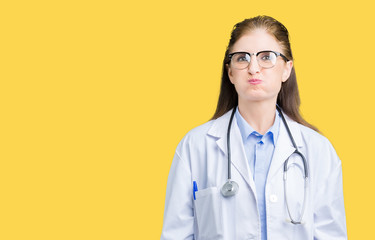 Middle age mature doctor woman wearing medical coat over isolated background puffing cheeks with funny face. Mouth inflated with air, crazy expression.