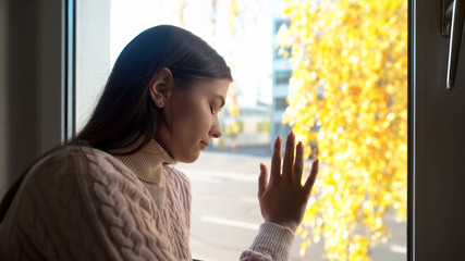 Crying woman touching window, felling sorrow and frustration, autumn depression