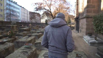 Man walking on cemetery, visiting grave of loved relative, feeling pain of loss