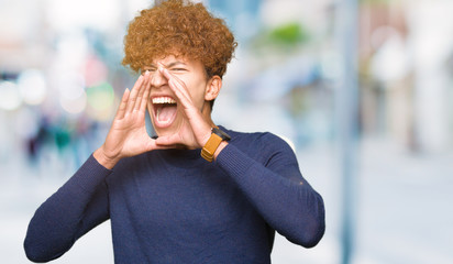 Young handsome man with afro hair Shouting angry out loud with hands over mouth