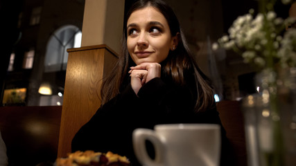 Smiling woman sitting in restaurant and flirting with admirer, romantic date